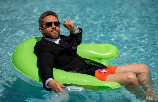 Funny business man in a business suit works for a laptop standing in the water in pool