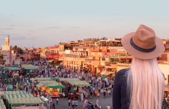 young woman in a beige hat watches people in the Jemma el Fnaa