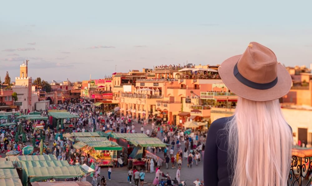 young woman in a beige hat watches people in the Jemma el Fnaa